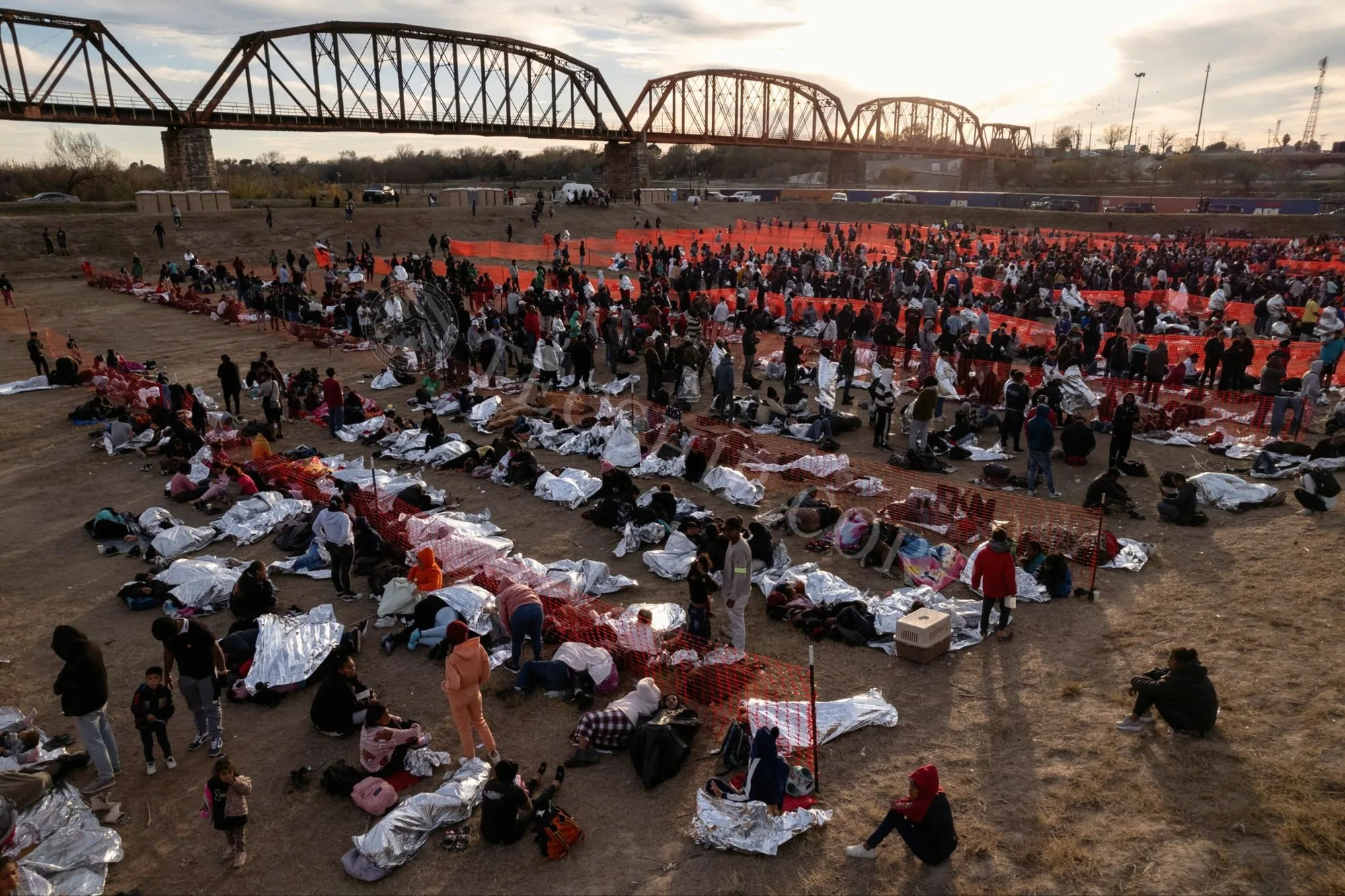 People sheltering under emergency mylar thermal blankets at a humanitarian relief site